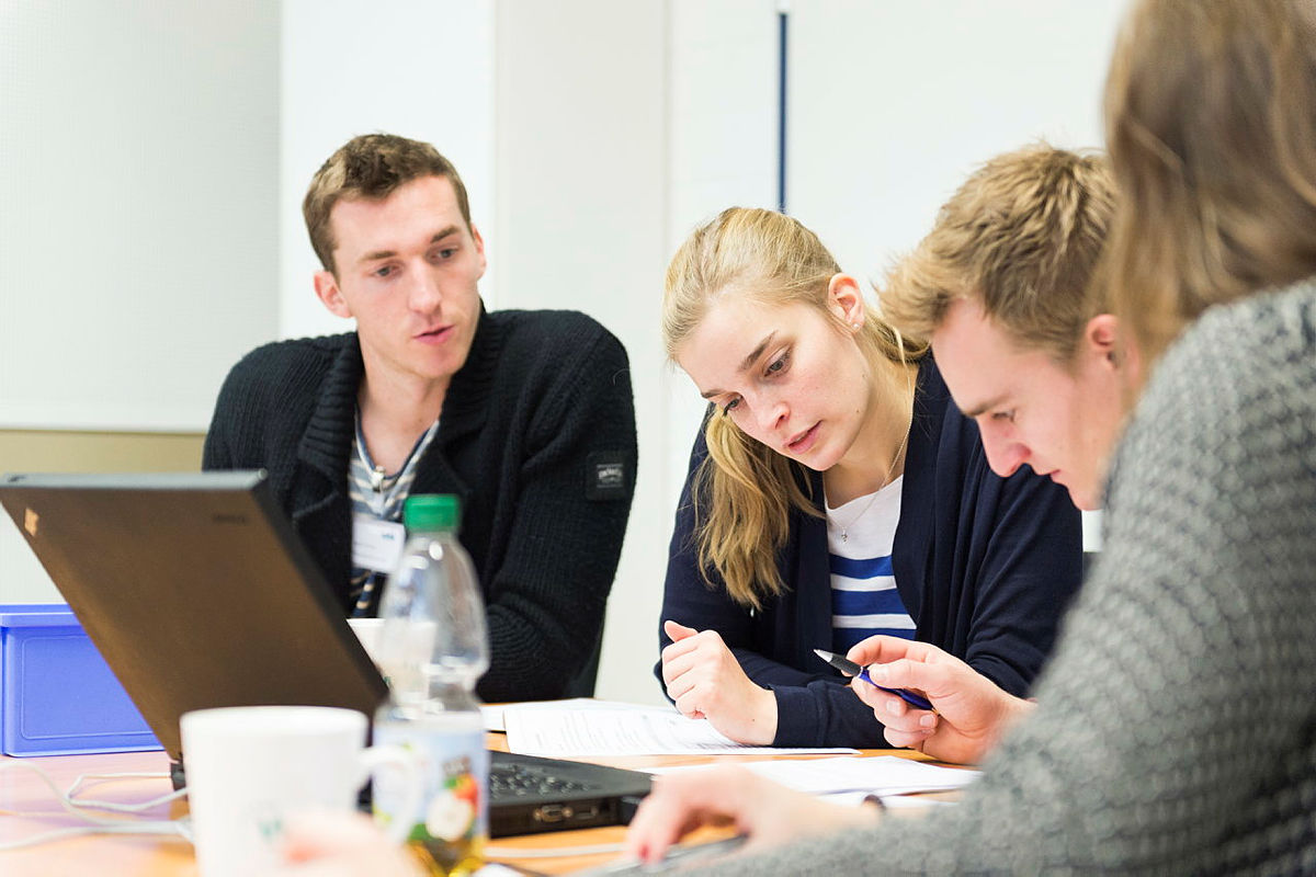 Studierende sitzen an einem Tisch und arbeiten gemeinsam