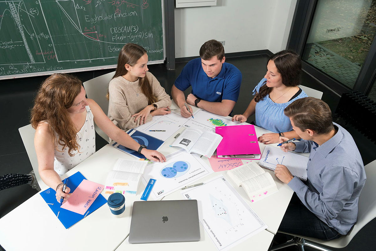 Studierende sitzen auf einem Tisch und arbeiten gemeinsam