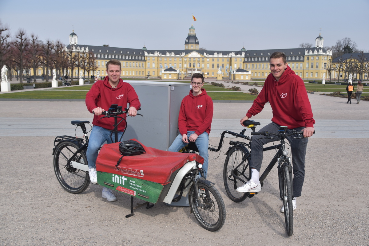 3 Personen stehen mit Fahrrädern vor dem Schloss in Karlsruhe
