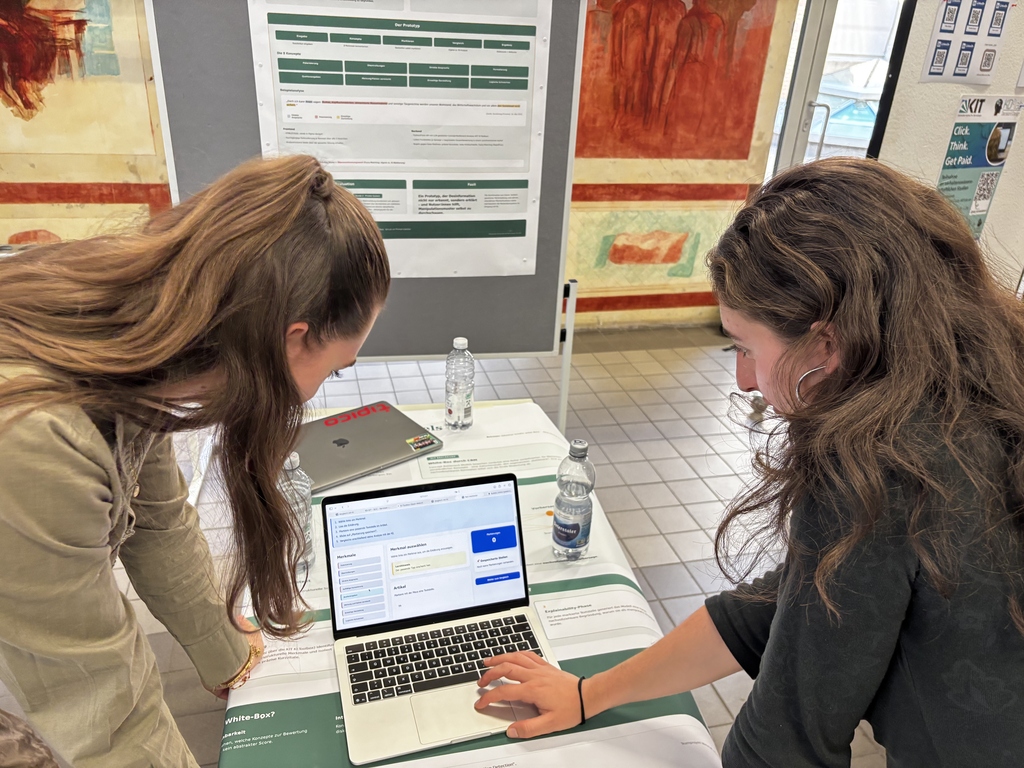 Zwei Frauen analysieren gemeinsam einen Software-Prototyp auf einem Laptop.