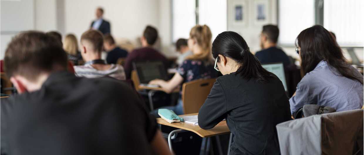 Studierende am Tisch, schreibend